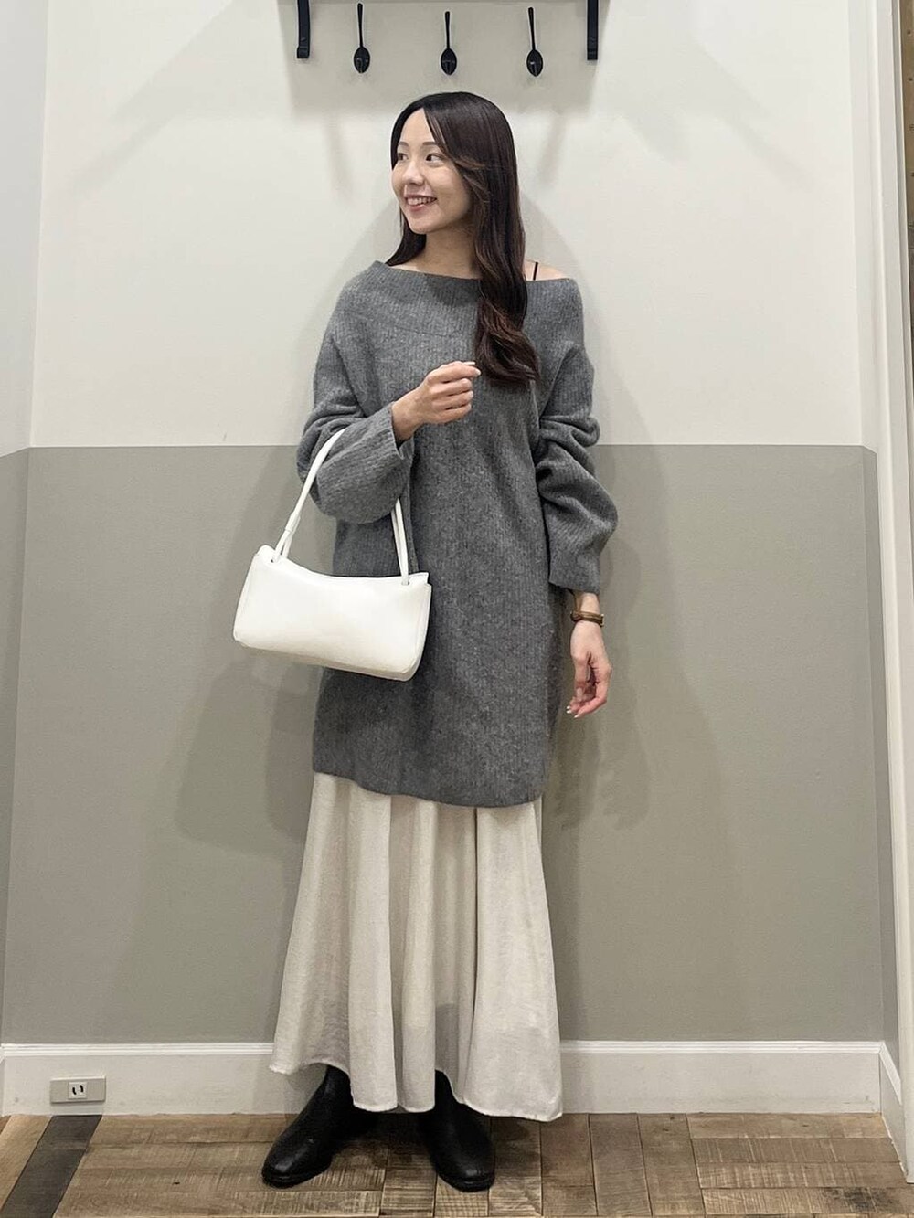 グレー系のワンピース、ホワイト系のスカート、ホワイト系のショルダーバッグを着用したレディースの冬コーディネートの2枚目の写真