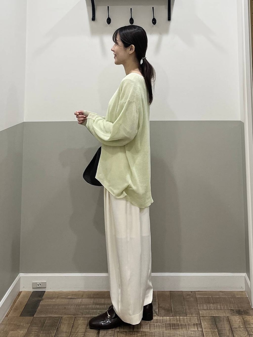 ホワイト系のスラックス、ブラウン系のショルダーバッグ、グリーン系のニット/セーターを着用したレディースの春コーディネートの5枚目の写真