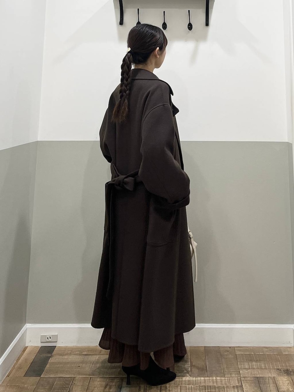 ブラウン系のステンカラーコート、ホワイト系のニット/セーター、ブラウン系のスカートを着用したレディースの秋コーディネートの5枚目の写真