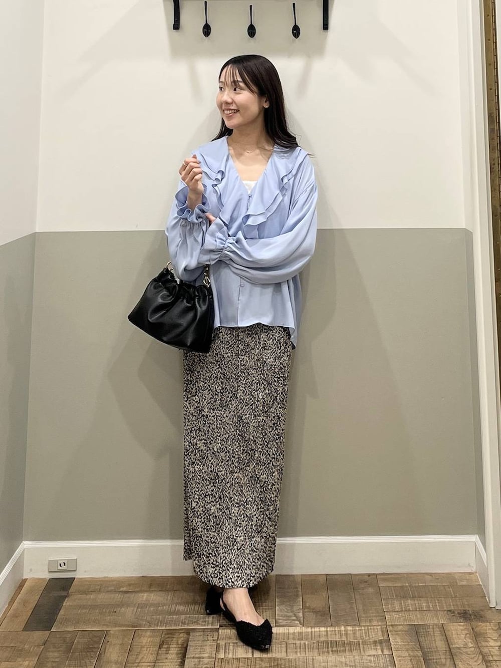 ベージュ系のスカート、ブラック系のショルダーバッグ、ホワイト系のキャミソールを着用したレディースの冬コーディネートの2枚目の写真