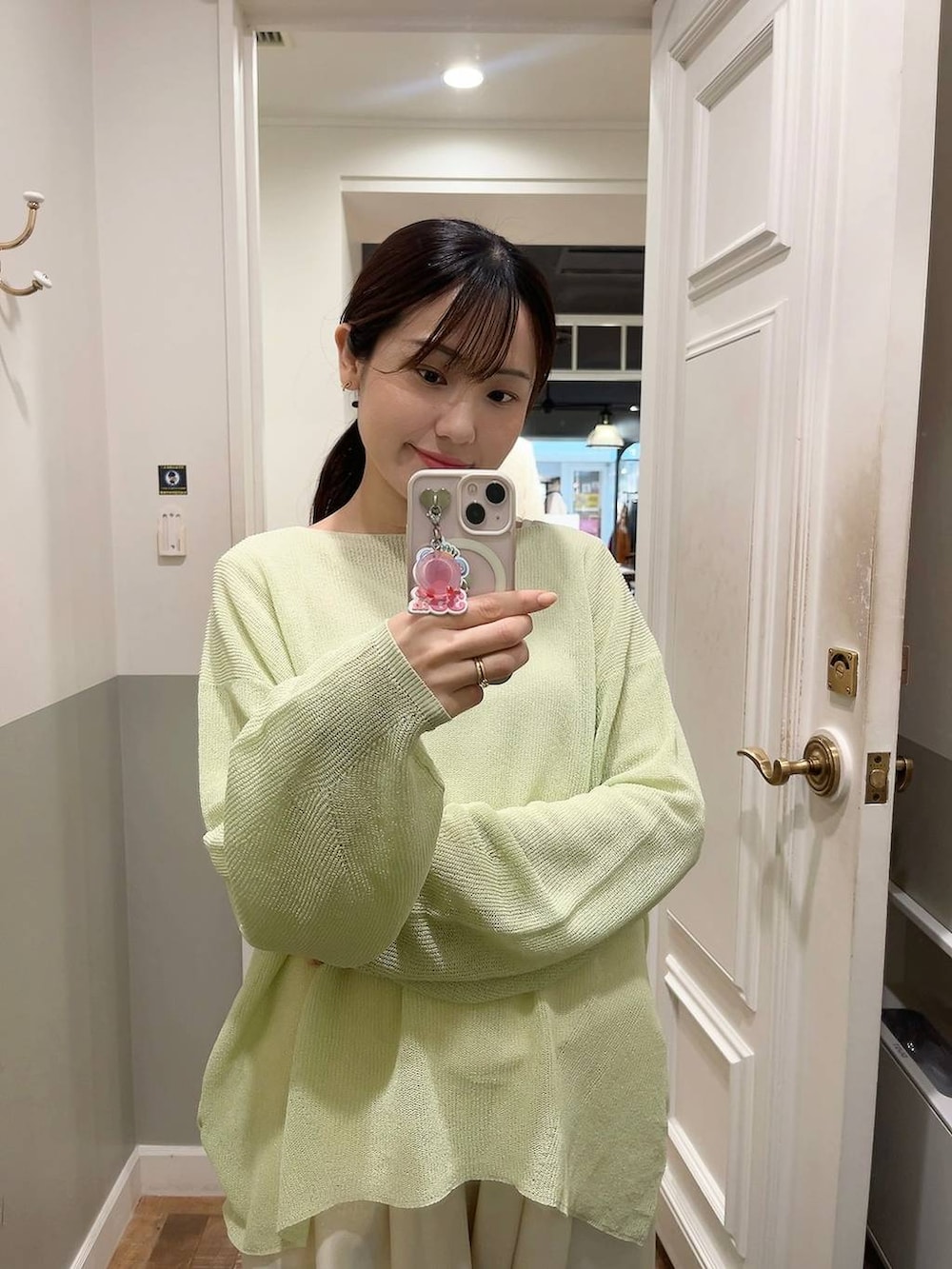 ホワイト系のスラックス、ブラウン系のショルダーバッグ、グリーン系のニット/セーターを着用したレディースの春コーディネートの2枚目の写真