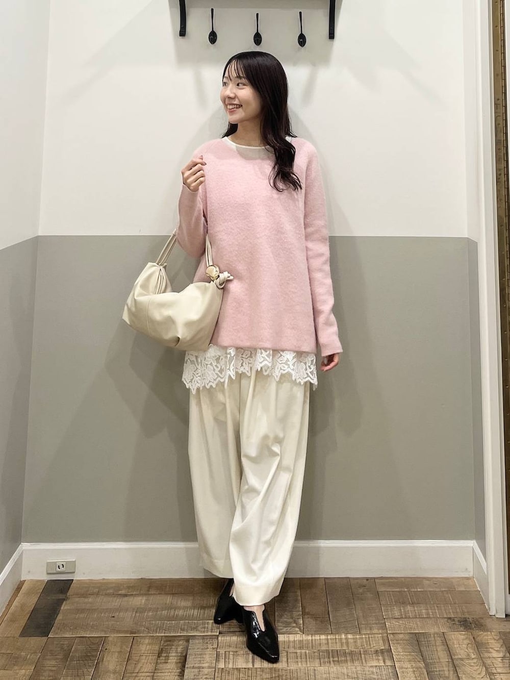 ピンク系のニット/セーター、ホワイト系のスラックス、ホワイト系のキャミソールを着用したレディースの冬コーディネートの4枚目の写真