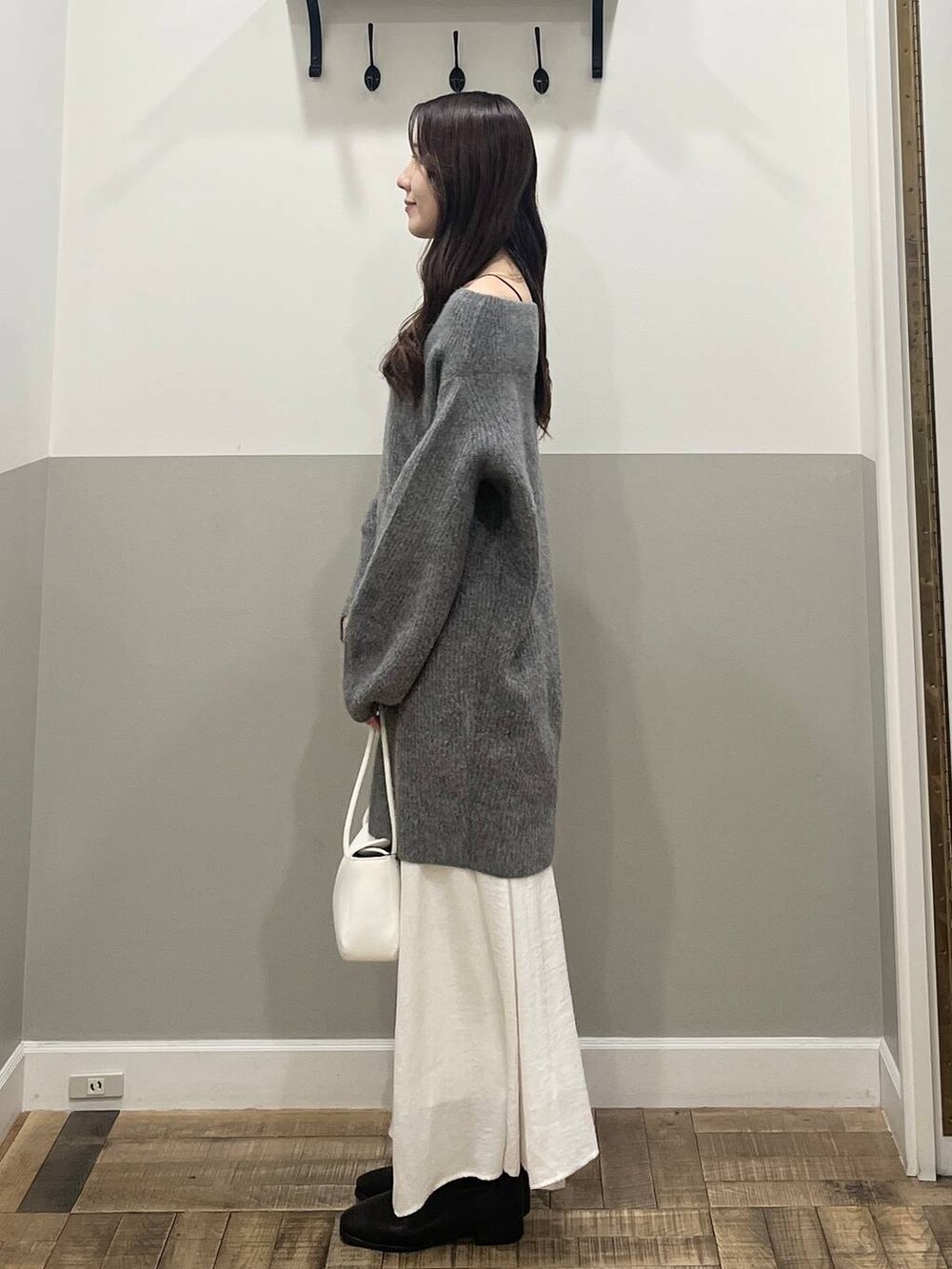 グレー系のワンピース、ホワイト系のスカート、ホワイト系のショルダーバッグを着用したレディースの冬コーディネートの3枚目の写真