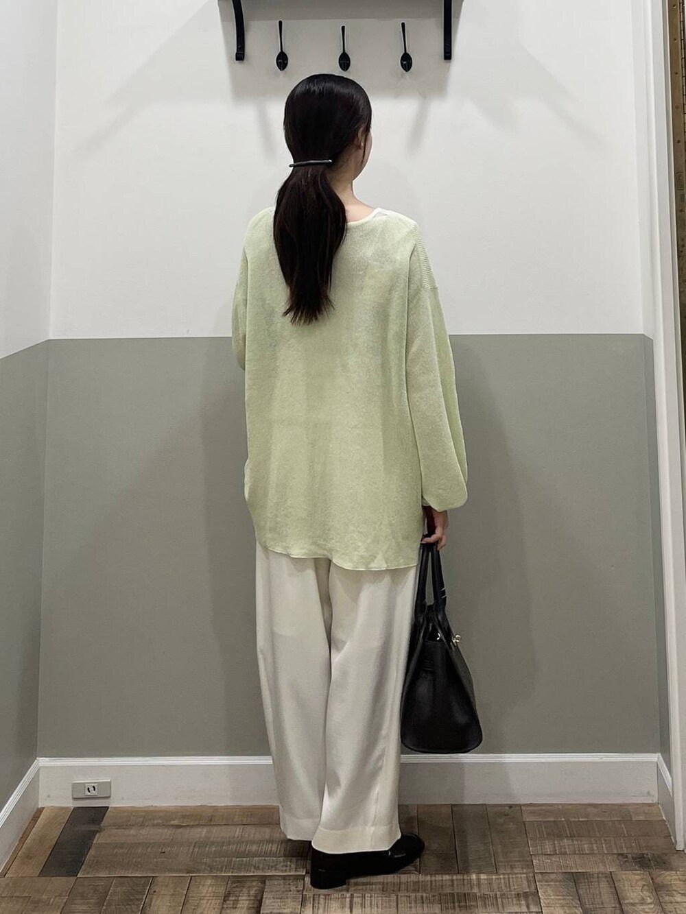 ホワイト系のスラックス、ブラウン系のショルダーバッグ、グリーン系のニット/セーターを着用したレディースの春コーディネートの6枚目の写真