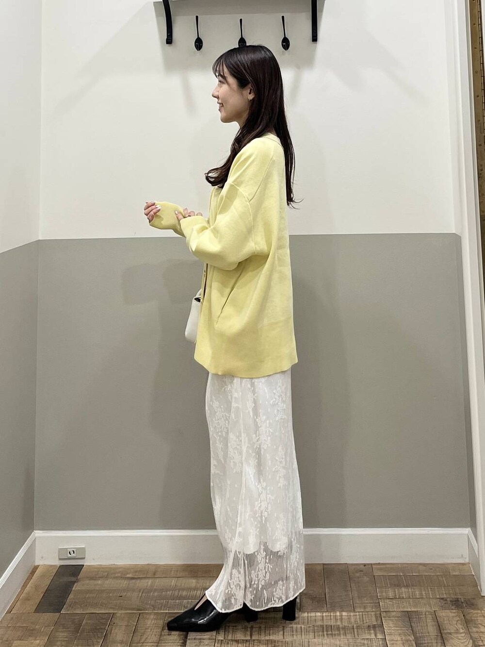 イエロー系のカーディガン/ボレロ、ブラック系のパンプス、ホワイト系のスカートを着用したレディースの春コーディネートの3枚目の写真