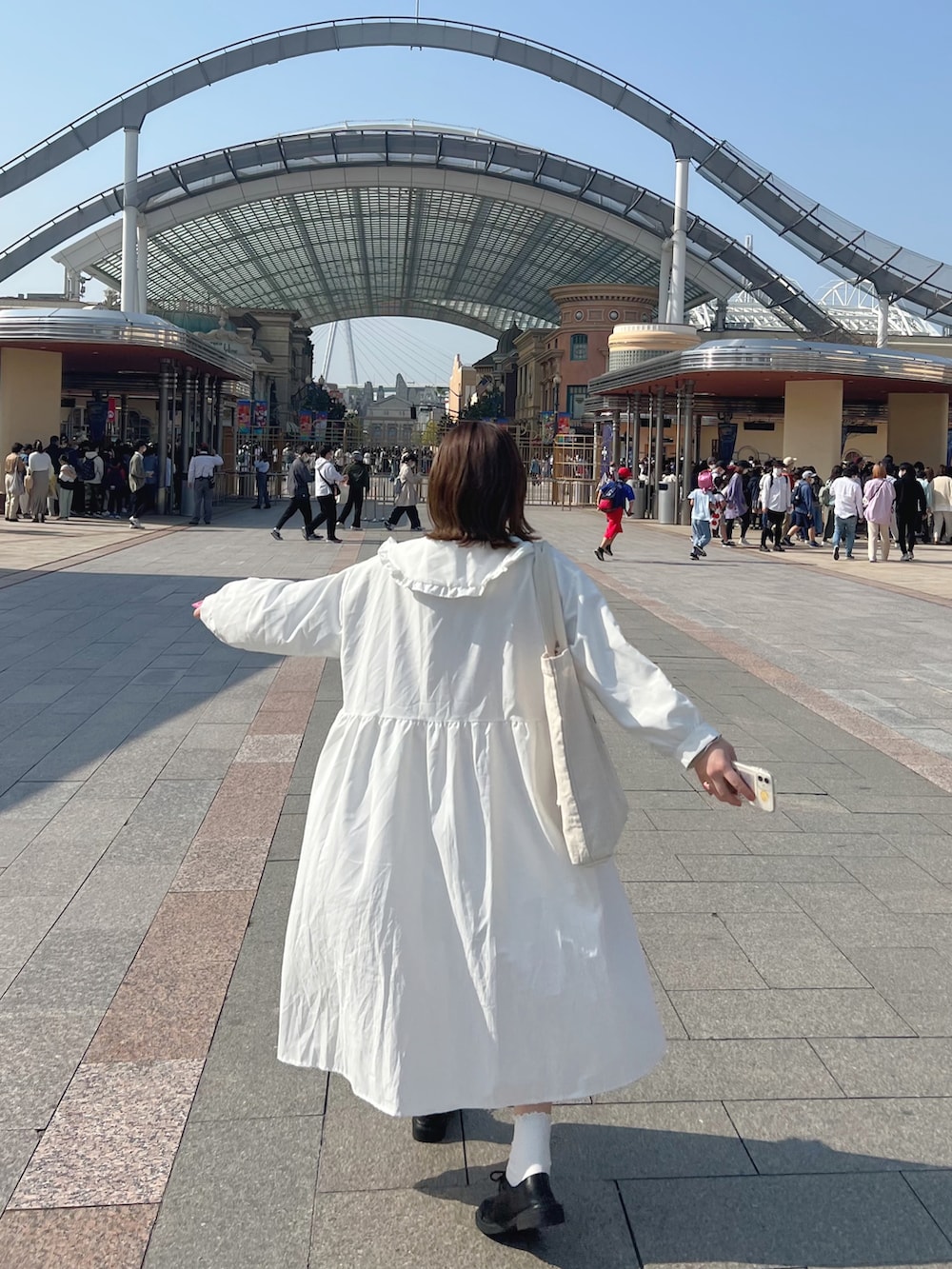 ホワイト系のワンピース、ベージュ系のトートバッグ、ブラック系のドレスシューズを着用したレディースの春コーディネートの2枚目の写真