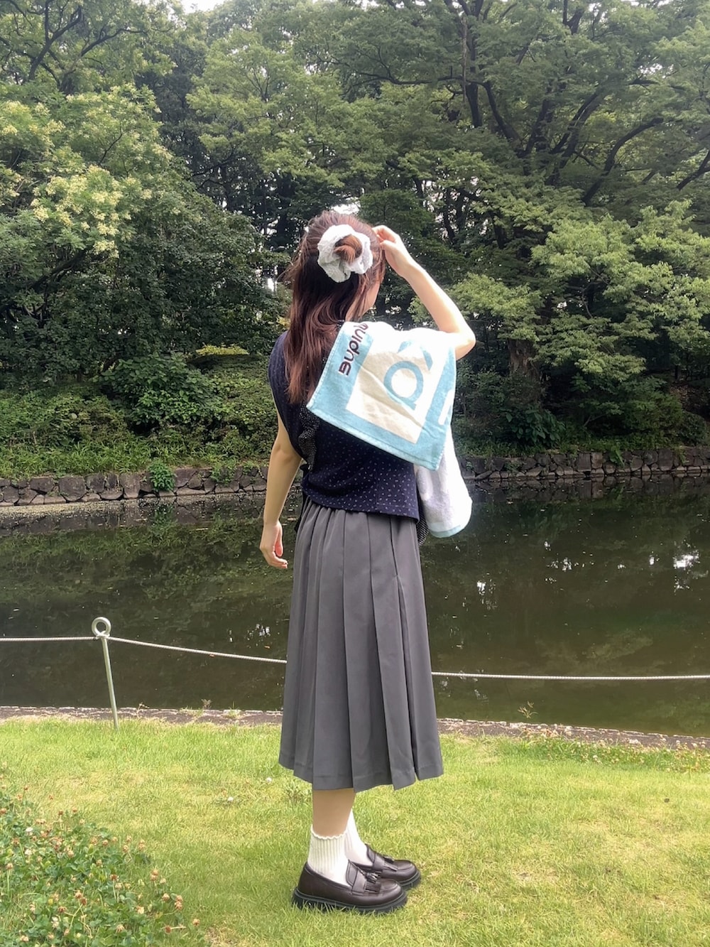 グレー系のスカート、ブルー系のTシャツ/カットソー、グレー系のハンドバッグを着用したレディースの秋コーディネートの3枚目の写真