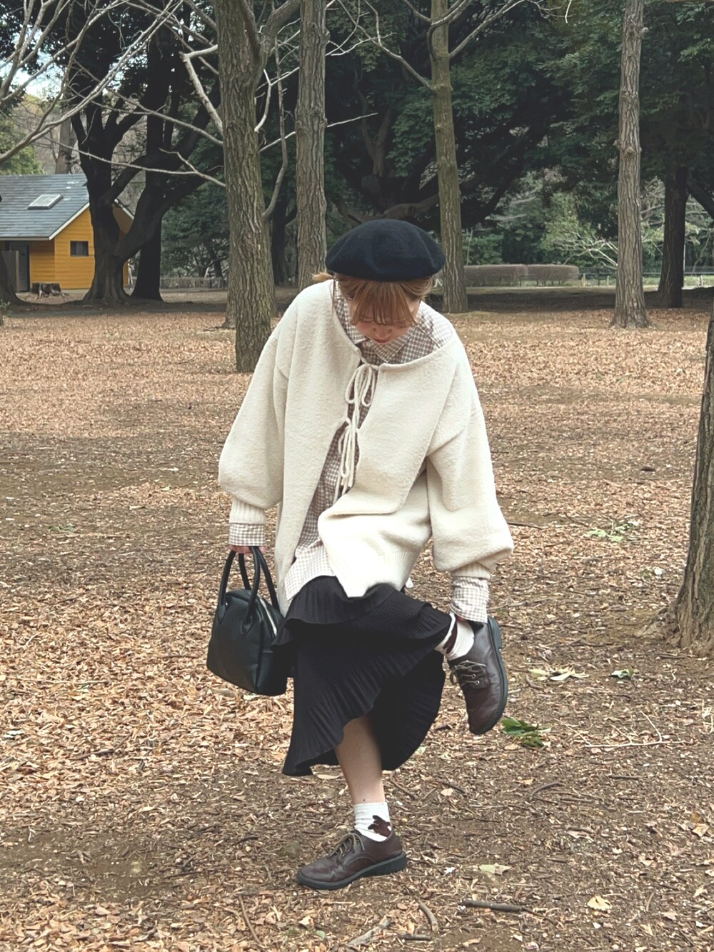 ホワイト系のニット/セーター、ベージュ系のシャツ/ブラウス、ブラック系のショルダーバッグを着用したレディースの春コーディネートの2枚目の写真