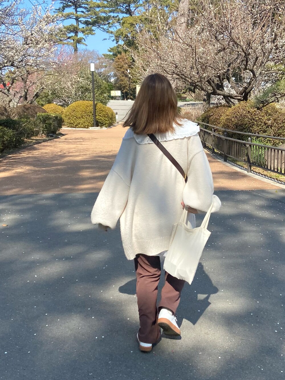 ホワイト系のスニーカー、ホワイト系のシャツ/ブラウス、ホワイト系のニット/セーターを着用したレディースの春コーディネートの2枚目の写真