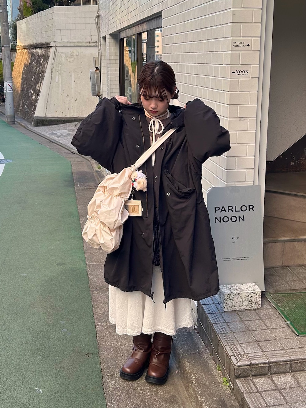 ブラック系のモッズコート、ホワイト系のショルダーバッグ、ホワイト系のTシャツ/カットソーを着用したレディースの冬コーディネートの2枚目の写真