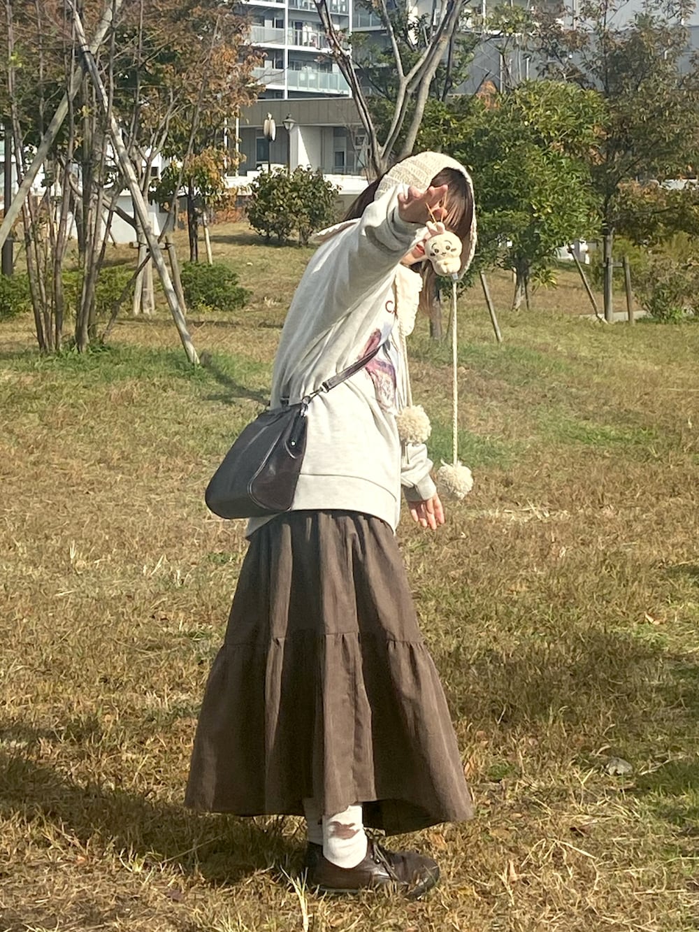 ブラウン系のスカート、ベージュ系のスウェット、ホワイト系のシャツ/ブラウスを着用したレディースの秋コーディネートの2枚目の写真