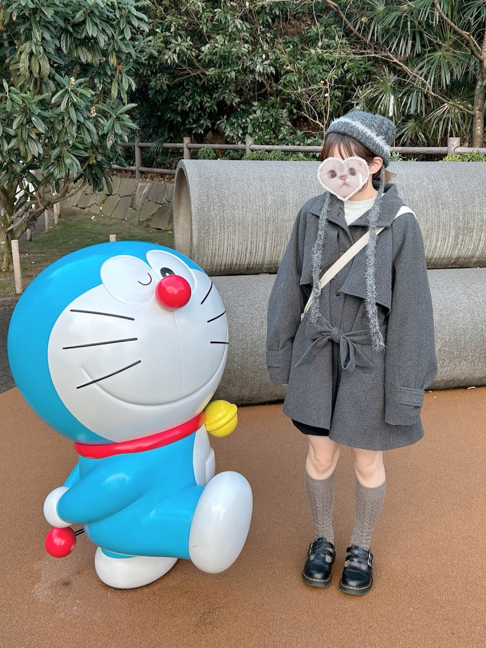 グレー系のトレンチコート、ブラック系のその他シューズ、グレー系の帽子を着用したレディースの冬コーディネートの2枚目の写真