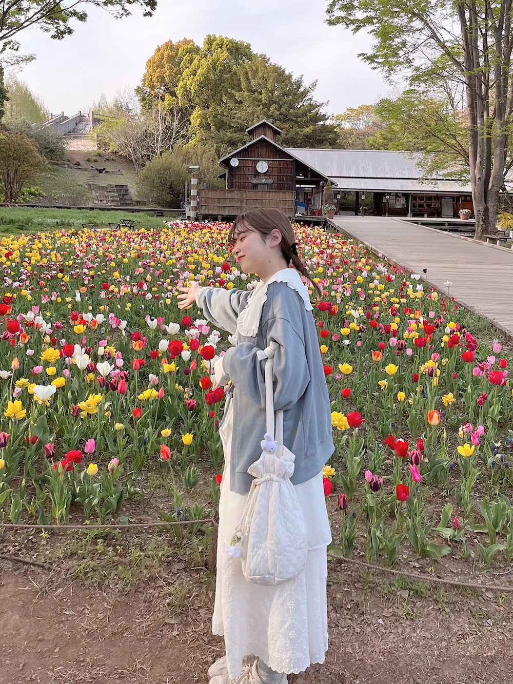 ホワイト系のハンドバッグ、ホワイト系のスカート、ブルー系のTシャツ/カットソーを着用したレディースの夏コーディネートの2枚目の写真