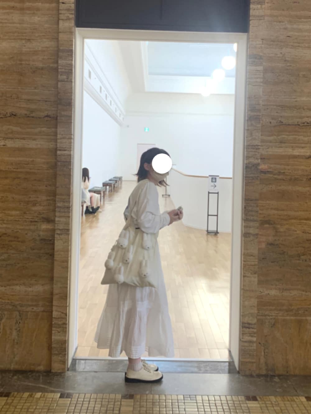 ホワイト系のトートバッグ、ブラック系のドレスシューズ、ホワイト系のスカートを着用したレディースの秋コーディネートの2枚目の写真