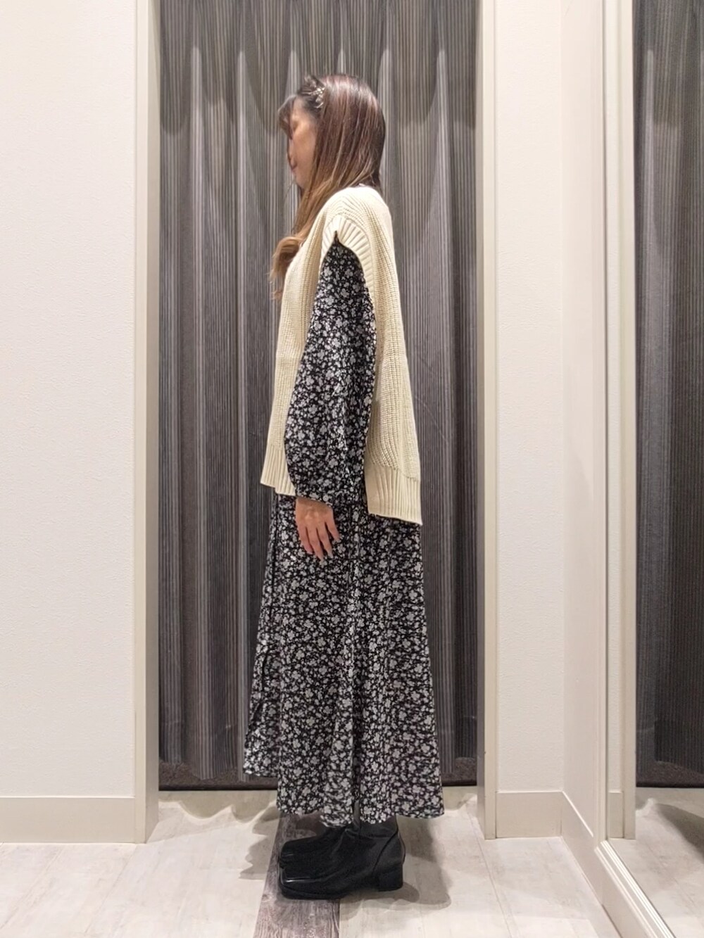 ブラック系のブーツ、ブラック系のワンピース、ホワイト系のベストを着用したレディースの秋コーディネートの2枚目の写真