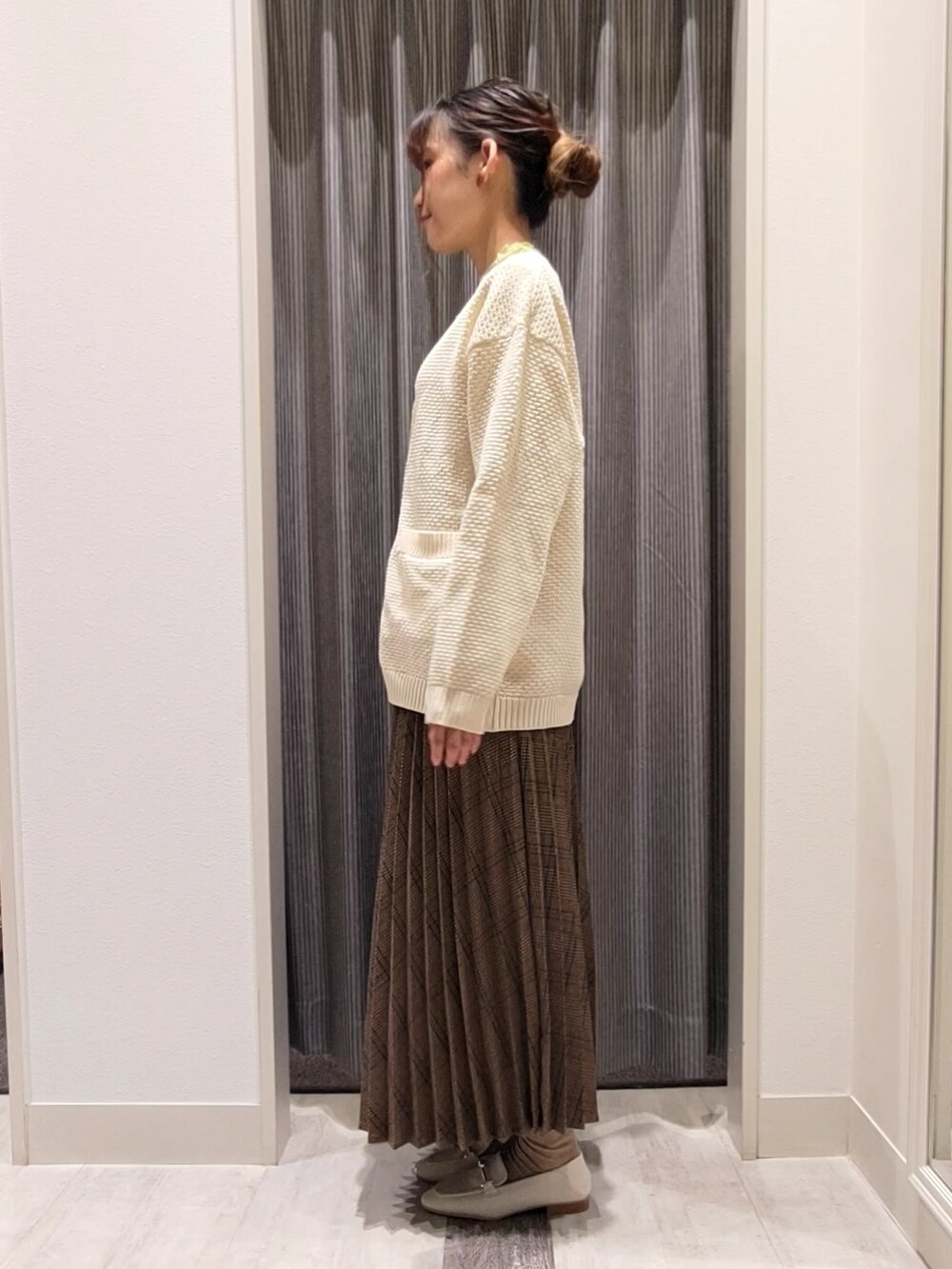 ホワイト系のカーディガン/ボレロ、グリーン系のニット/セーター、ブラウン系のスカートを着用したレディースの秋コーディネートの2枚目の写真