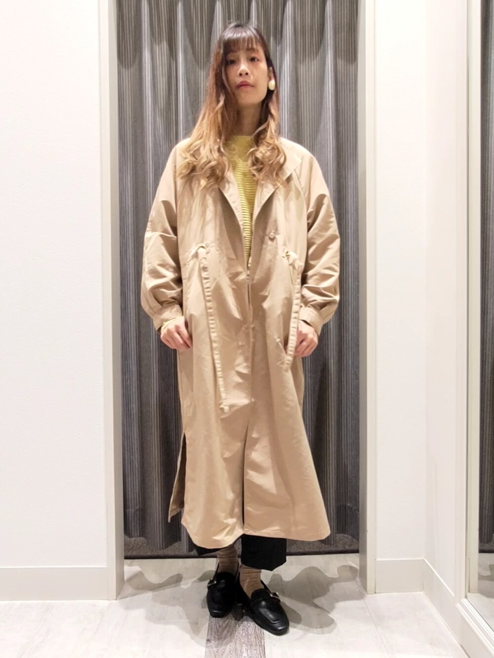 ベージュ系のその他アウター、イエロー系のニット/セーター、ブラック系のドレスシューズを着用したレディースの秋コーディネートの4枚目の写真