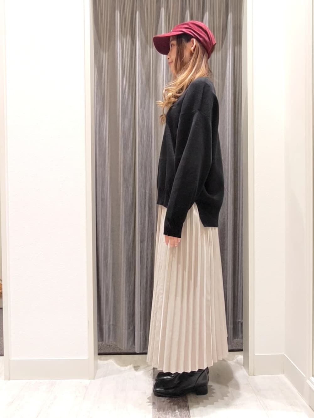 ブラック系のニット/セーター、グレー系のスカート、ブラック系のブーツを着用したレディースの秋コーディネートの2枚目の写真