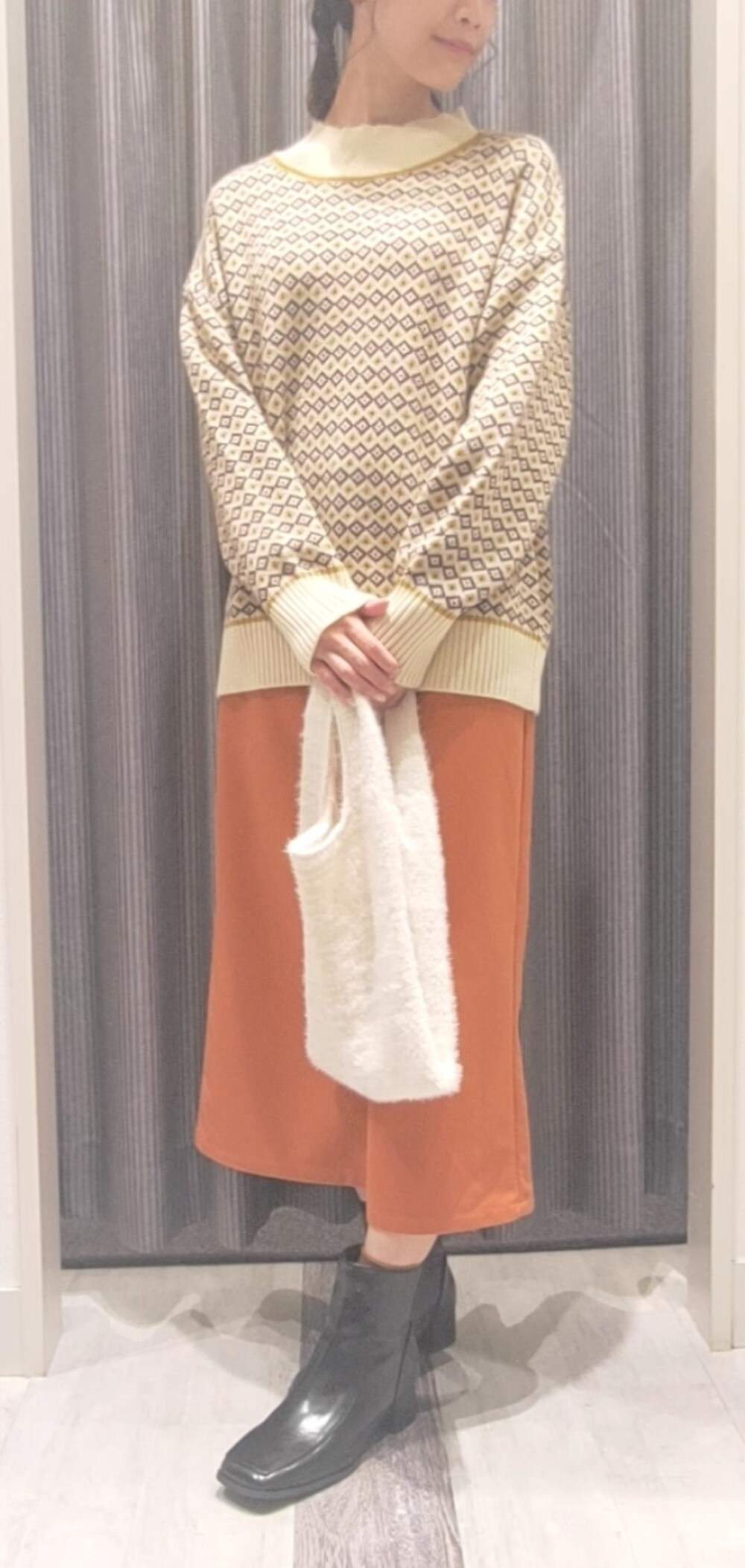 ホワイト系のハンドバッグ、ブラック系のブーツ、イエロー系のニット/セーターを着用したレディースの秋コーディネートの5枚目の写真