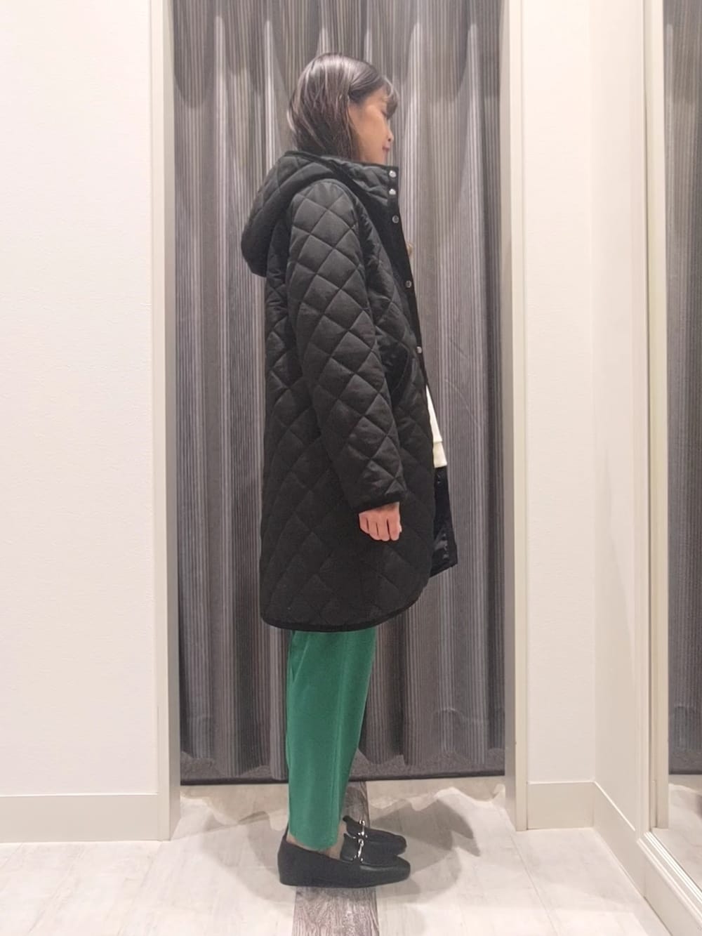 ホワイト系のニット/セーター、ブラック系のその他アウター、グリーン系のその他パンツを着用したレディースの冬コーディネートの2枚目の写真