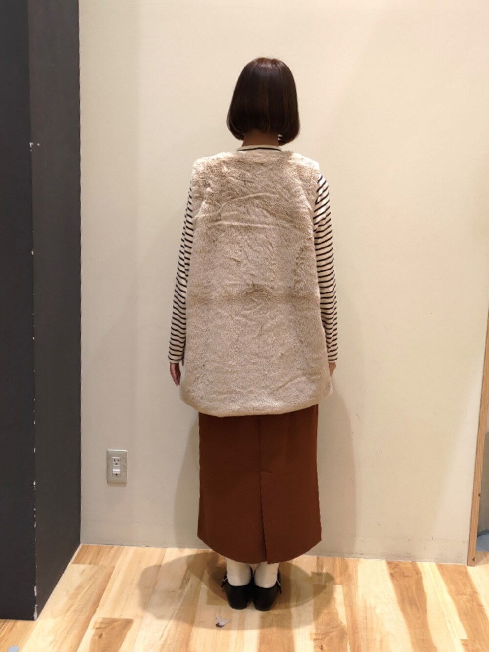 ベージュ系のベスト、オレンジ系のスカート、ブラック系のドレスシューズを着用したレディースの秋コーディネートの3枚目の写真