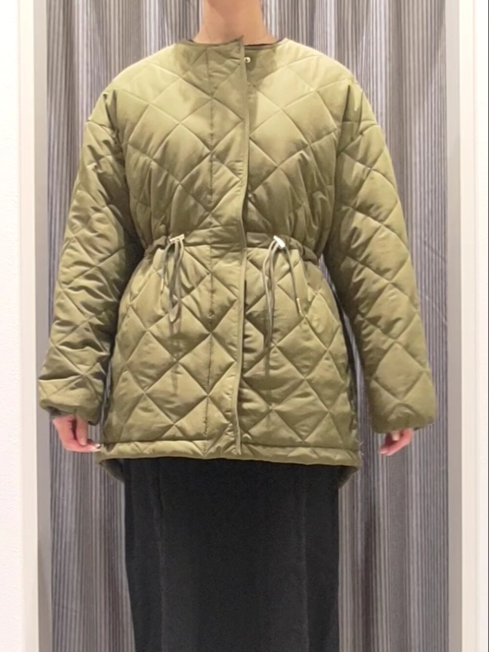 グリーン系のブルゾン、ブラック系のワンピース、ブラック系のブーツを着用したレディースの秋コーディネートの4枚目の写真