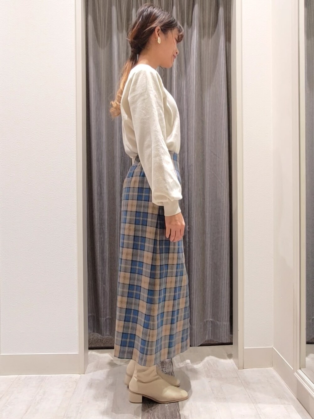 ホワイト系のブーツ、グリーン系のスカート、ホワイト系のニット/セーターを着用したレディースの秋コーディネートの2枚目の写真