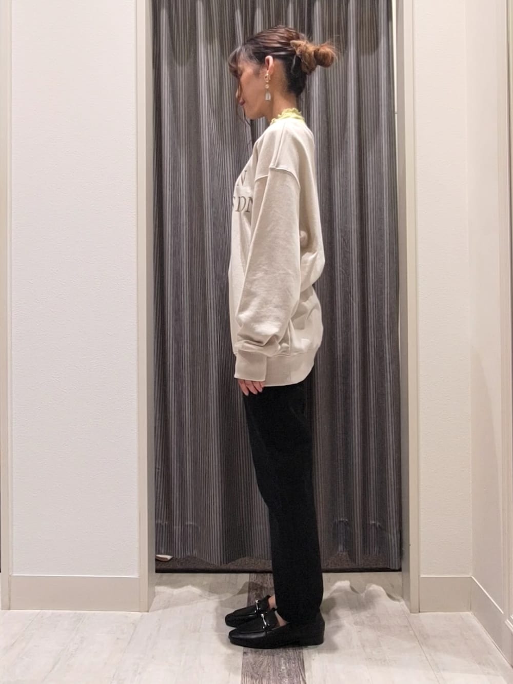 ブラック系のデニムパンツ、ブラック系のドレスシューズ、イエロー系のハンドバッグを着用したレディースの秋コーディネートの2枚目の写真