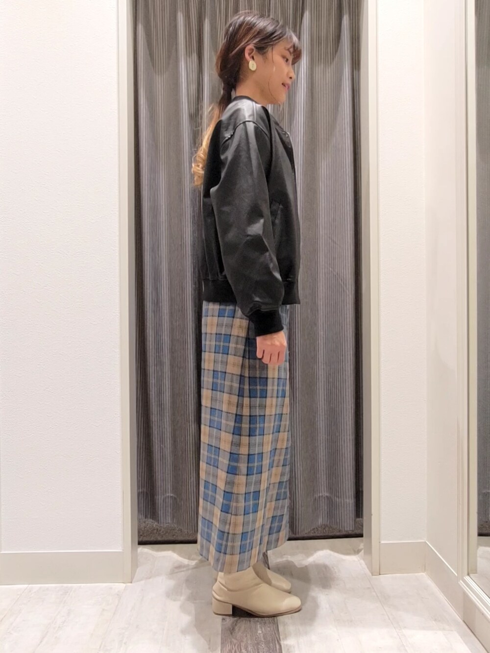 ホワイト系のニット/セーター、ブラック系のブルゾン、グリーン系のスカートを着用したレディースの秋コーディネートの2枚目の写真