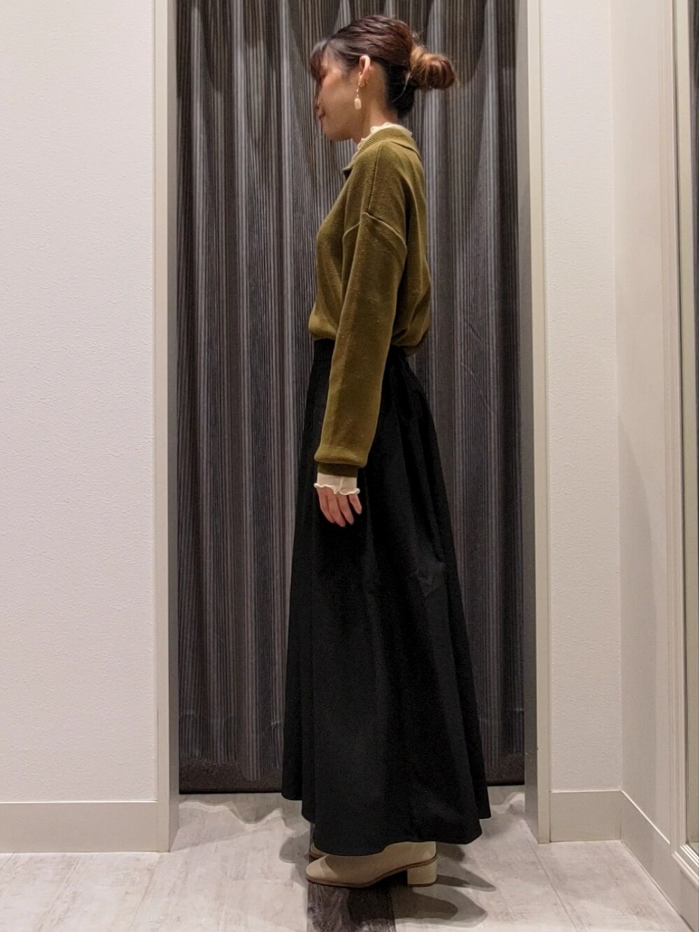 ブラック系のスカート、ホワイト系のブーツ、グリーン系のニット/セーターを着用したレディースの秋コーディネートの2枚目の写真