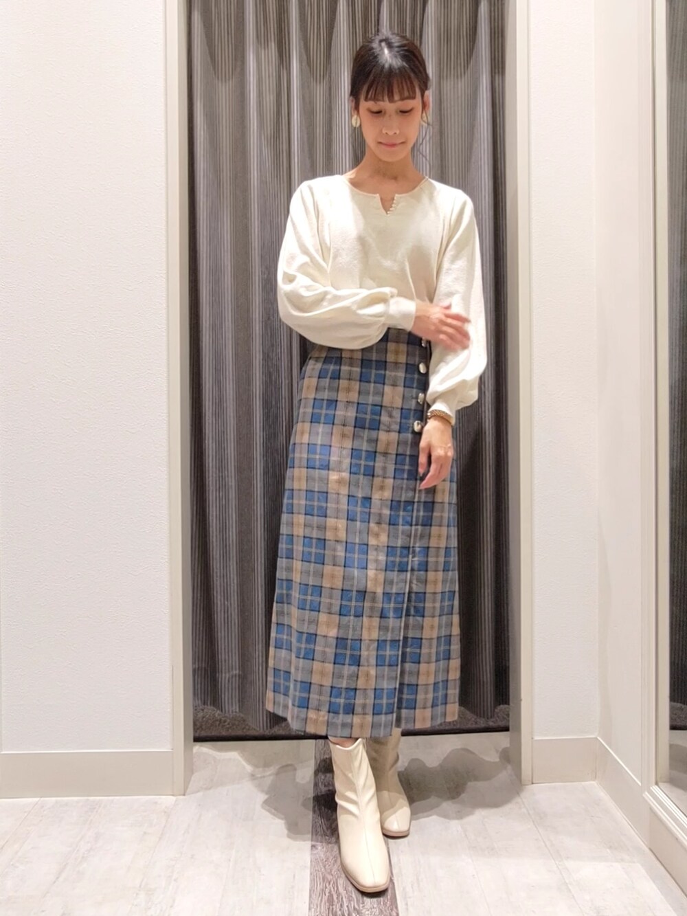 ホワイト系のニット/セーター、ブラック系のブルゾン、グリーン系のスカートを着用したレディースの秋コーディネートの4枚目の写真