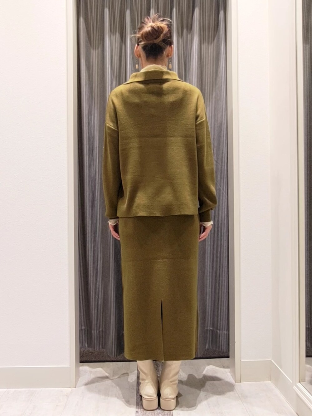 グリーン系のニット/セーター、グリーン系のスカート、ホワイト系のブーツを着用したレディースの秋コーディネートの3枚目の写真