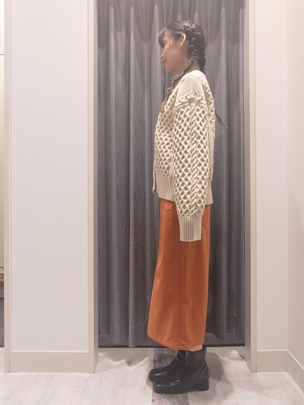 ホワイト系のカーディガン/ボレロ、オレンジ系のスカート、ブラック系のブーツを着用したレディースの秋コーディネートの3枚目の写真