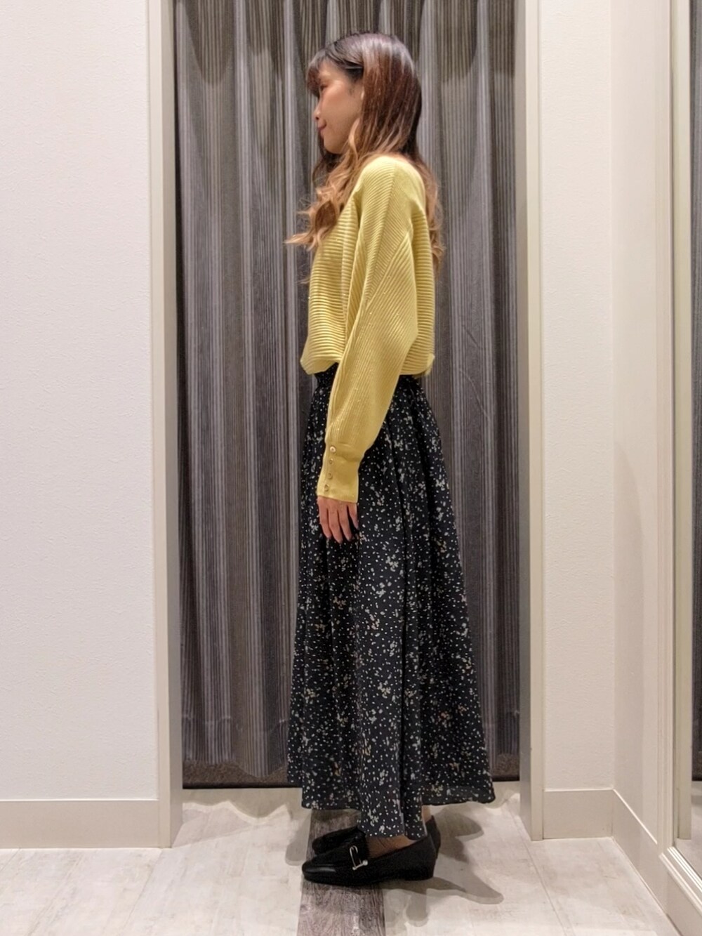 ブルー系のスカート、イエロー系のニット/セーター、ブラック系のドレスシューズを着用したレディースの秋コーディネートの2枚目の写真