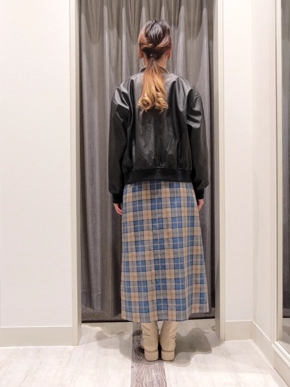 ホワイト系のニット/セーター、ブラック系のブルゾン、グリーン系のスカートを着用したレディースの秋コーディネートの3枚目の写真