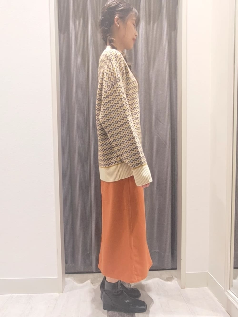 ホワイト系のハンドバッグ、ブラック系のブーツ、イエロー系のニット/セーターを着用したレディースの秋コーディネートの3枚目の写真