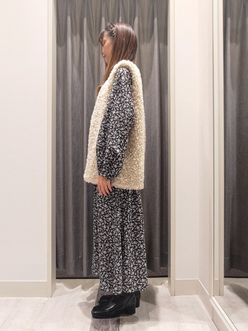 ホワイト系のベスト、ブラック系のワンピース、ブラック系のブーツを着用したレディースの秋コーディネートの2枚目の写真