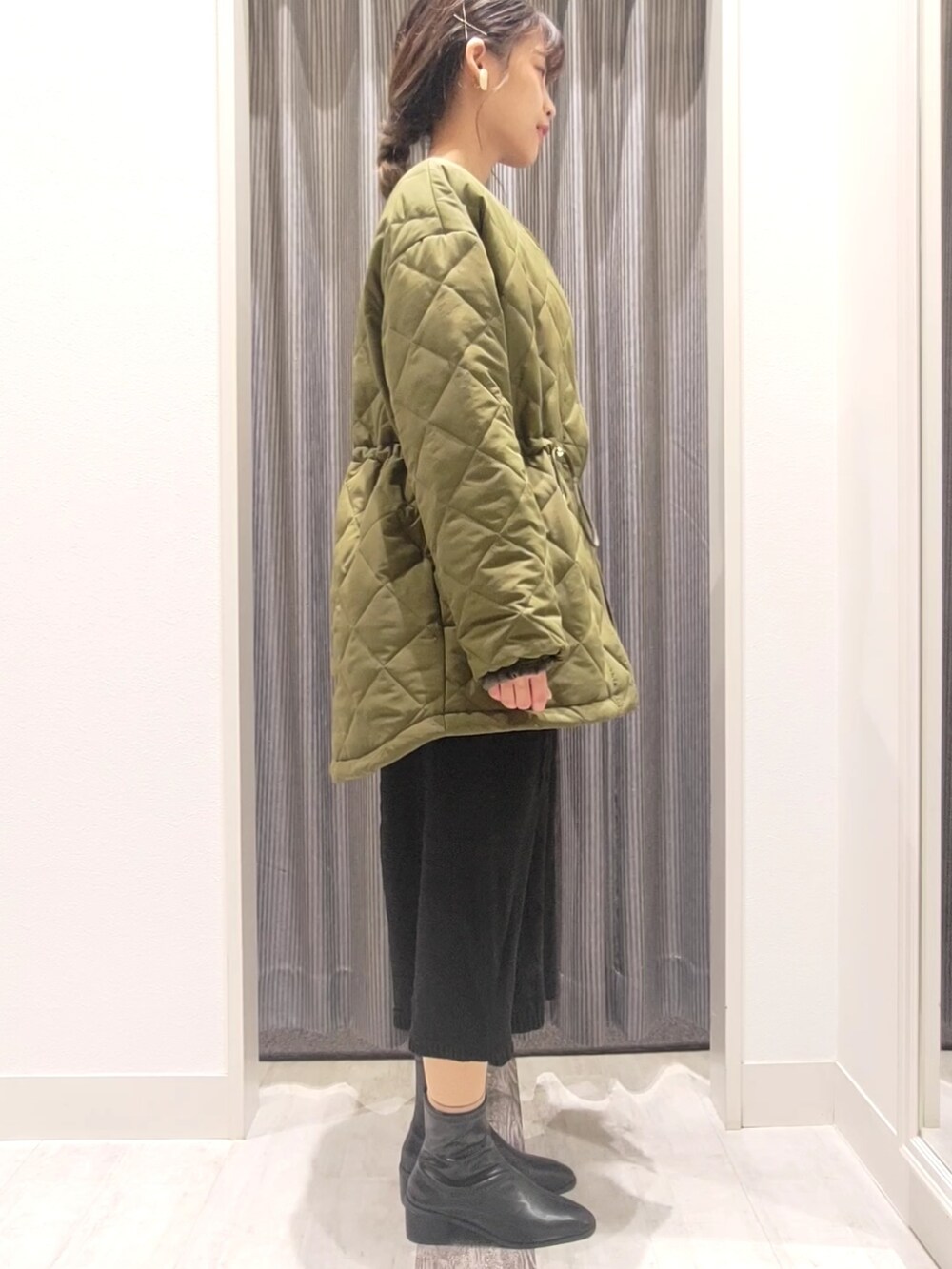 グリーン系のブルゾン、ブラック系のワンピース、ブラック系のブーツを着用したレディースの秋コーディネートの2枚目の写真