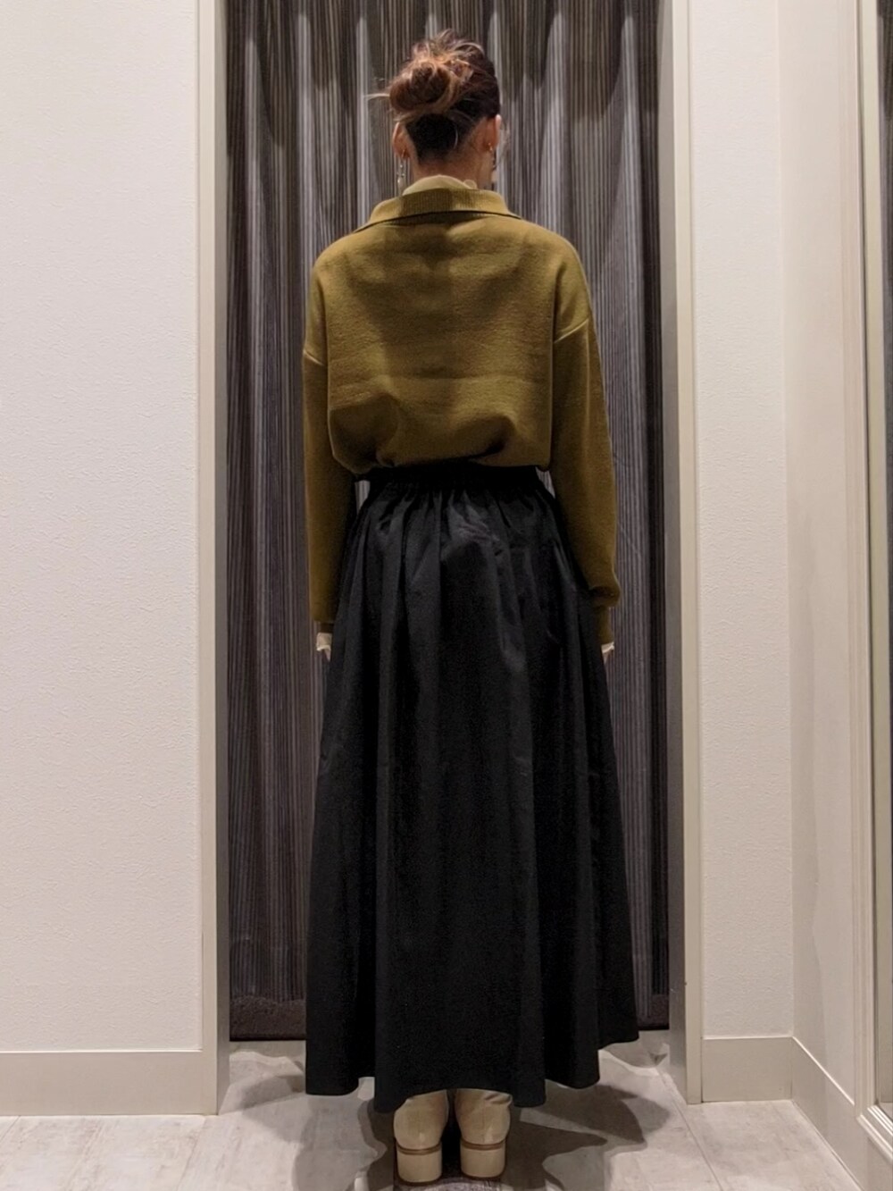 ブラック系のスカート、ホワイト系のブーツ、グリーン系のニット/セーターを着用したレディースの秋コーディネートの3枚目の写真