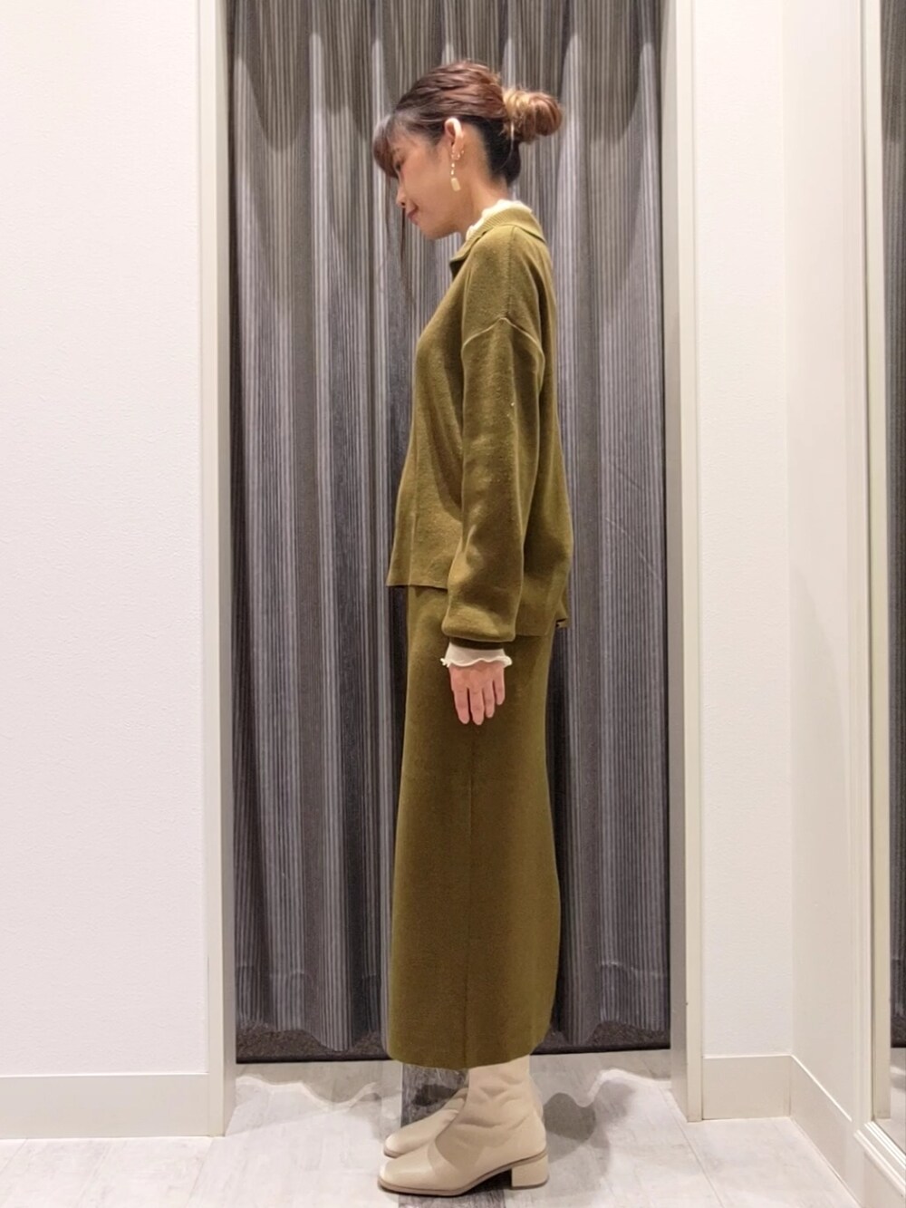 グリーン系のニット/セーター、グリーン系のスカート、ホワイト系のブーツを着用したレディースの秋コーディネートの2枚目の写真