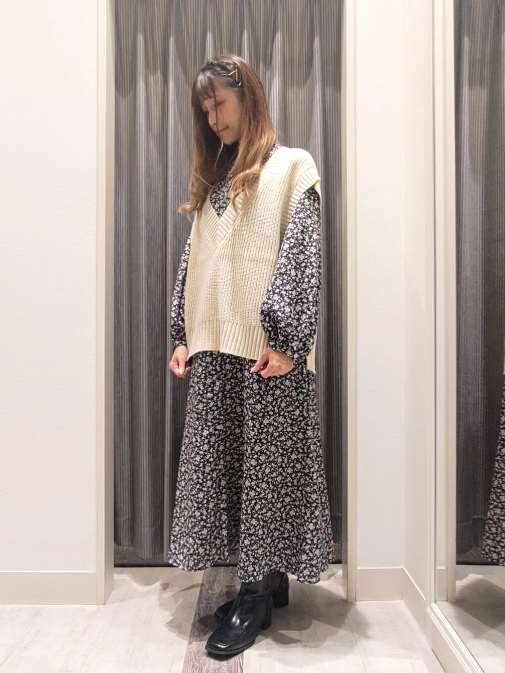 ホワイト系のベスト、ブラック系のワンピース、ブラック系のブーツを着用したレディースの秋コーディネートの4枚目の写真