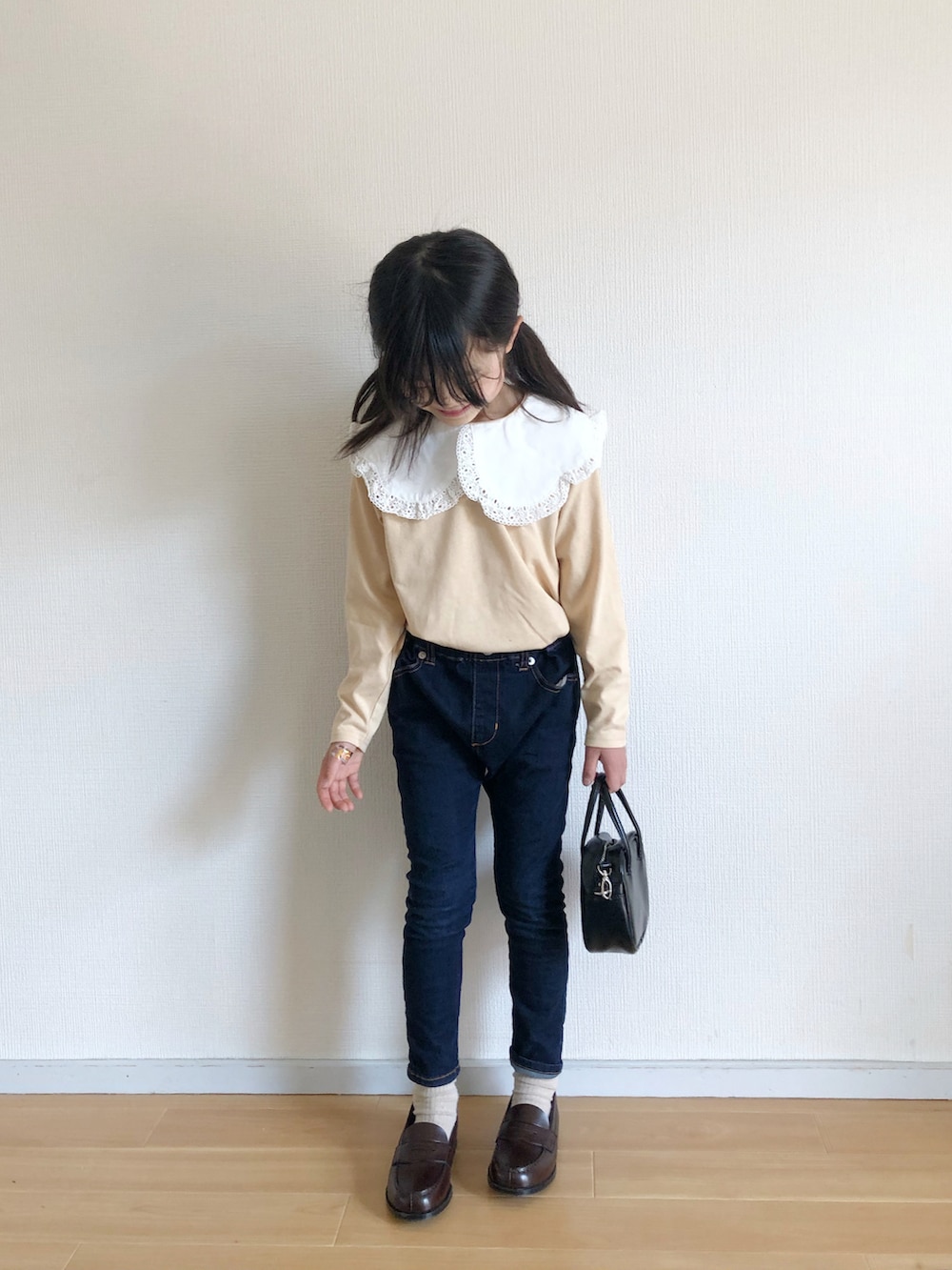 イエロー系のTシャツ/カットソー、ブルー系のデニムパンツ、ブラック系のハンドバッグを着用したキッズの春コーディネートの2枚目の写真