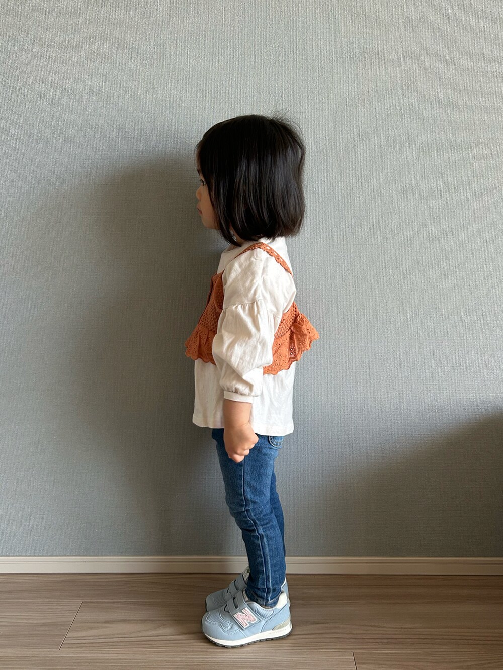 オレンジ系のトップス、ブルー系のベスト、ブルー系のデニムパンツを着用したキッズの春コーディネートの2枚目の写真