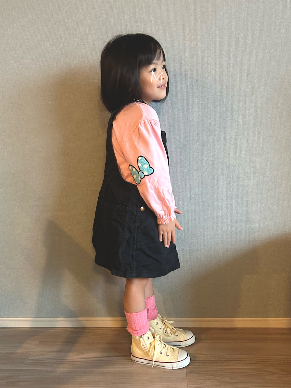 ブラック系のジャンパースカート、ピンク系のTシャツ/カットソー、ホワイト系のスニーカーを着用したキッズの秋コーディネートの3枚目の写真