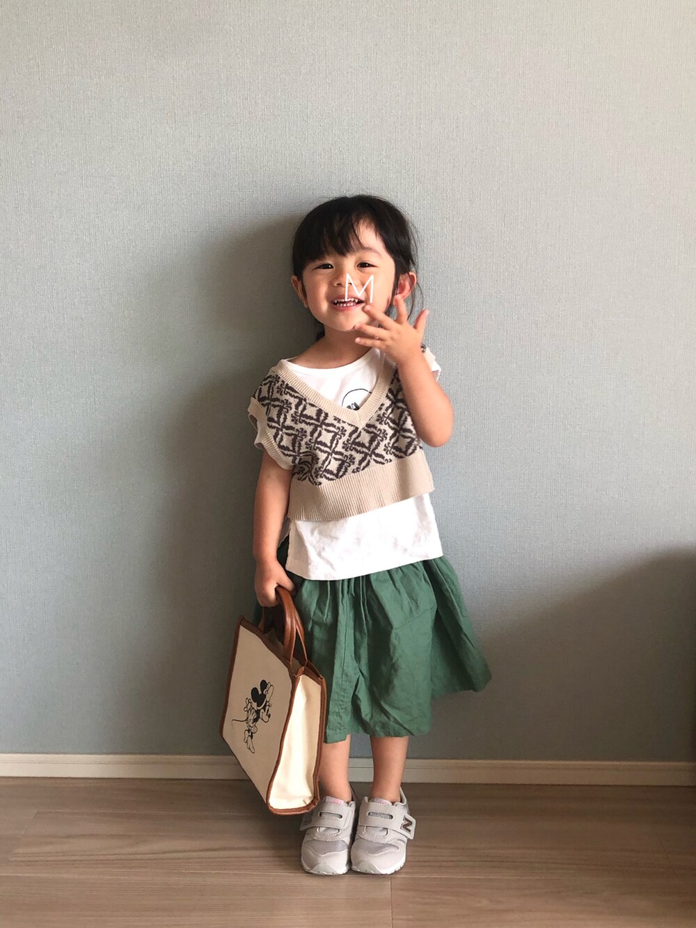 ベージュ系のベスト、ホワイト系のTシャツ/カットソー、グリーン系のスカートを着用したキッズの秋コーディネートの2枚目の写真