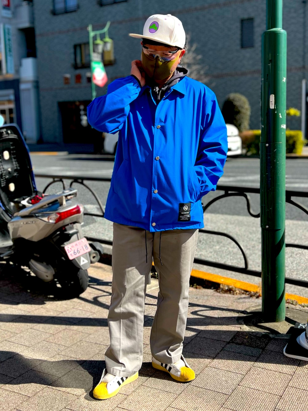 ブルー系のナイロンジャケット、シルバー系のチノパンツ、ホワイト系のスニーカーを着用したメンズの冬コーディネートの2枚目の写真