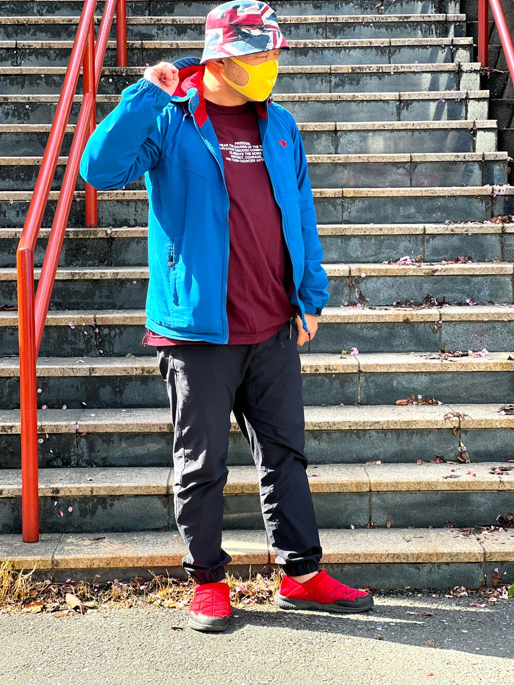 ブラック系のその他パンツ、レッド系のTシャツ/カットソー、ブルー系のマウンテンパーカーを着用したメンズの春コーディネートの2枚目の写真