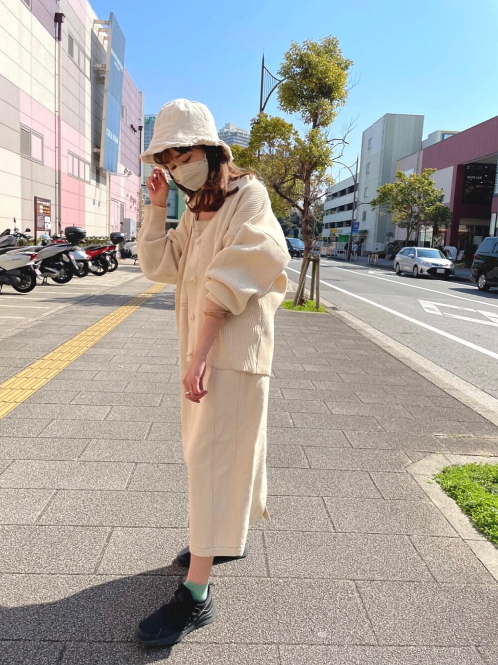 ベージュ系のカーディガン/ボレロ、ブルー系のジャンパースカート、ブラック系のスニーカーを着用したレディースの春コーディネートの2枚目の写真