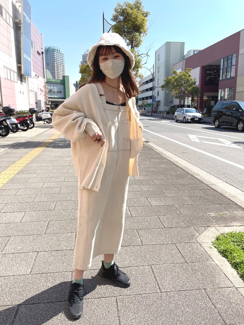 ベージュ系のカーディガン/ボレロ、ブルー系のジャンパースカート、ブラック系のスニーカーを着用したレディースの春コーディネートの4枚目の写真