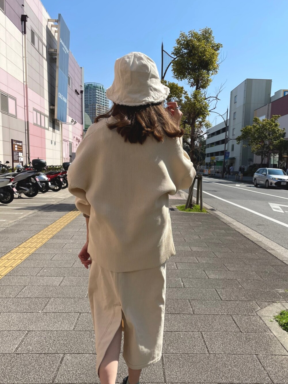 ベージュ系のカーディガン/ボレロ、ブルー系のジャンパースカート、ブラック系のスニーカーを着用したレディースの春コーディネートの3枚目の写真